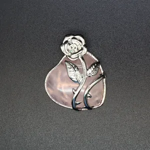Détail macro d'un pendentif coeur en quartz rose avec un motif de rose en métal argenté