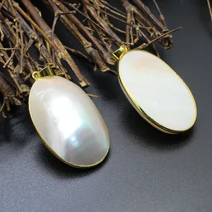 Macro detail of two iridescent oval mother of pearl pendants with gold-plated trim on twigs.