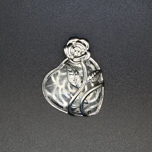 Vue détaillée d'un motif de rose argentée sur un pendentif en pierre naturelle en cœur.