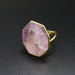 Gros plan d'une bague en pierre naturelle octogonale avec un anneau doré poli.