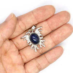 Detailansicht eines silbernen Mottenanhängers mit einem blauen Edelstein in der Hand