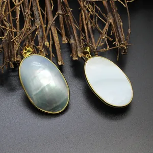 Close-up of oval natural mother of pearl pendants with iridescent shell and gold rim.