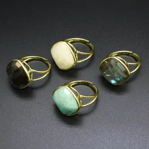 Detalle de anillos dorados ajustables con piedras naturales facetadas en varios colores