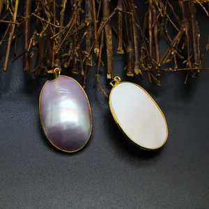 Detail view of oval natural mother-of-pearl pendants in pink and white gold frames