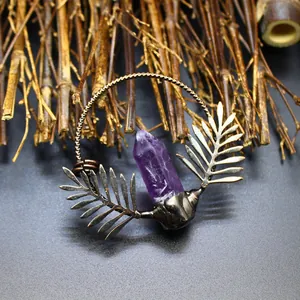 Detailed macro view of natural amethyst crystal pendant with vintage bronze leaf design.