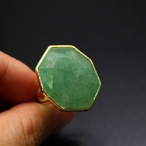 Gros plan d'une grande bague octogonale en pierre naturelle verte dorée