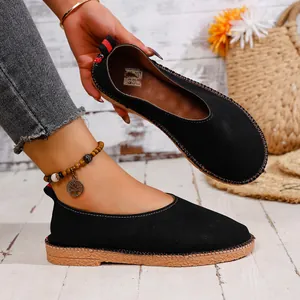 Close-up of black vintage round toe flats with woven sole and soft surface.