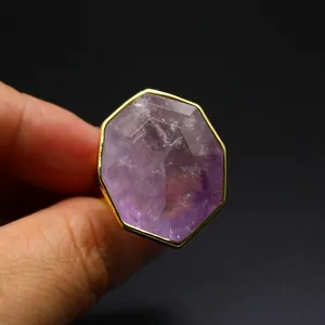 Gros plan d'une bague en cristal naturel violet facetté avec un cadre doré élégant.