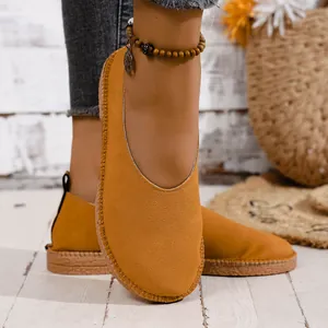 Close-up of retro mustard yellow suede loafers with hand-stitched sole on model