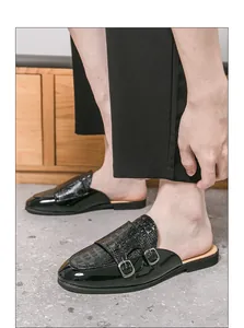 Primer plano de mocasines negros para hombre sin talón con hebillas y textura de coco.