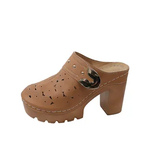Detailed view of tan leather platform mules with hollow-out floral patterns and gold buckle
