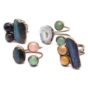 Detail view of handmade copper rings featuring various natural raw stones