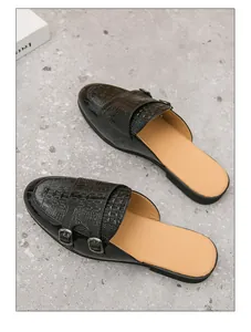 Vista detallada de los mules negros para hombre con relieve de cocodrilo y hebillas