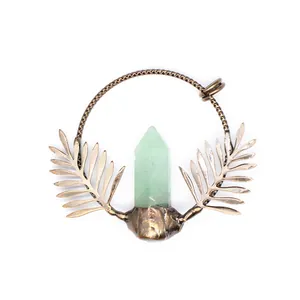Detailed view of retro bronze pendant featuring a green crystal point and leaf accents