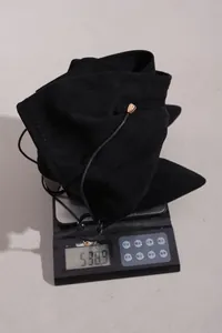 Detail shot showing the weight of a black suede over-the-knee boot on a digital scale
