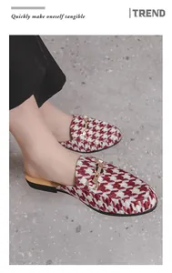 Macro view of red and white houndstooth patterned men's mule loafers with gold horsebit