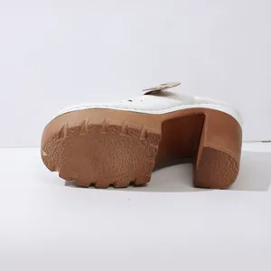 Detailed view of white platform mules with chunky brown heels and anti-slip rubber soles