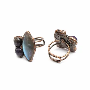 Close-up of irregular copper rings featuring blue labradorite and amethyst stones.