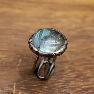 Dettaglio di un anello vintage ossidato con una pietra naturale iridescente