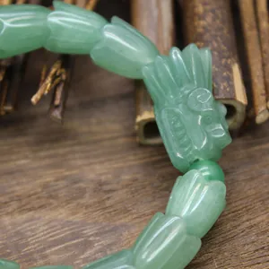 Detaillierte Nahaufnahme der aufwendigen Drachenkopf-Schnitzerei auf einem grünen Steinarmband