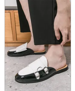 Detalle de mules de cuero blanco y negro para hombre con doble hebilla y textura croco