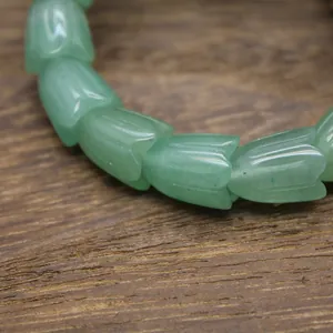 Nahaufnahme eines grünen Natursteinarmbands mit zarten tulpenförmigen Schnitzperlen