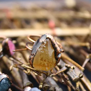 Primo piano di una citrina gialla grezza incastonata in un anello vintage di rame stile boho.