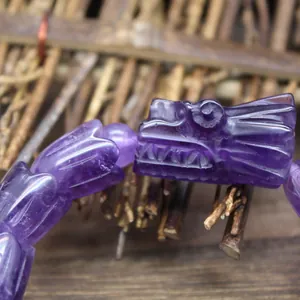 Makrodetail eines handgeschnitzten Drachenkopfs aus Amethyst an einem Ethno-Armband