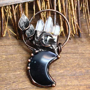 Detailed close-up of a vintage bronze moon pendant with natural clear crystals and leaves