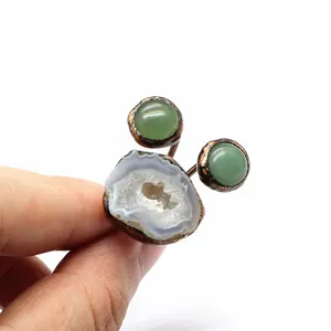 Close-up of handmade three-stone ring with natural druzy crystal and green gems