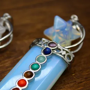 Close-up of 7 Chakra stone Merkaba star crystal sword pendant on wood background