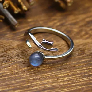 Macro detail of a silver open ring featuring a cute cat head and blue natural stone