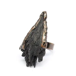 Macro di un anello con cristallo di tormalina nera grezza e fascia in bronzo anticato