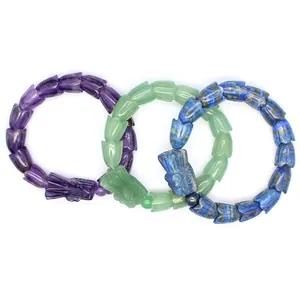 Detailansicht von drei Drachenarmbändern aus Naturstein in Lila, Grün und Blau.