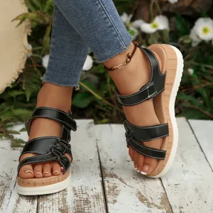 Close-up detail of black wedge sandals featuring crossover straps and thick platform soles