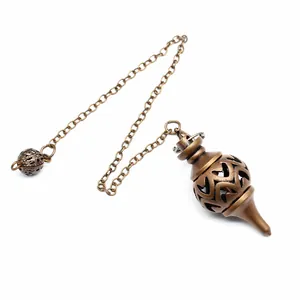 Dettaglio di un pendolo da divinazione in ottone vintage con motivi a cuore traforati