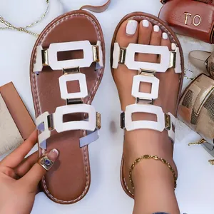 Vue détaillée de sandales plates blanches découpées avec des boucles dorées chic