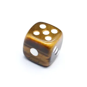 Detalle de un dado de piedra natural de ojo de tigre hecho a mano con puntos blancos grabados