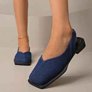 Dettaglio della trama in denim e del cinturino elastico del sandalo piatto con punta quadrata.