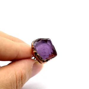 Primo piano di un anello in ametista viola grezza con castone in rame vintage in mano