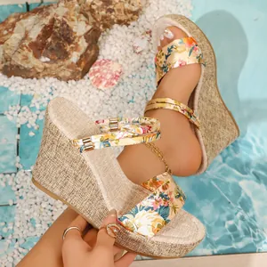 Détail de sandales compensées à fleurs avec talon plateforme tissé et bout ouvert
