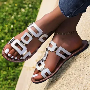 Sandales plates blanches élégantes avec découpes géométriques et boucles dorées aux pieds