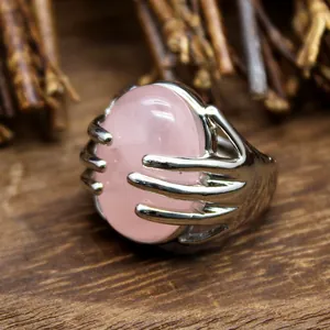 Detail of hand-shaped silver ring holding a large oval pink natural stone crystal