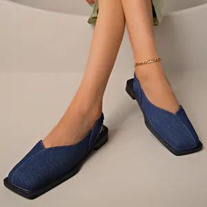 Dettaglio macro di sandali in denim blu a tacco basso con punta quadrata e cinturino elastico