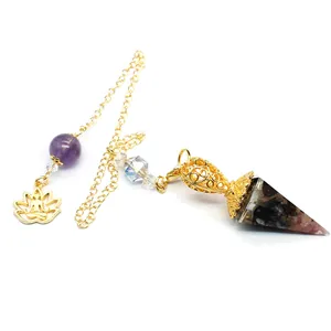 Detail of crystal resin hexagonal dowsing pendulum with gold chain and lotus charm