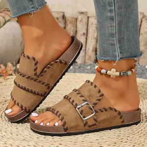 Close-up detail of vintage brown suede flat sandals featuring contrast stitching and buckle