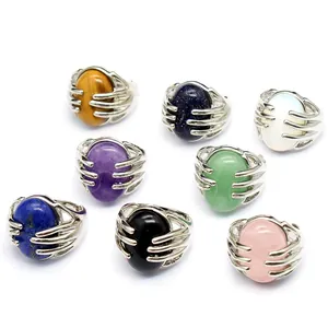 Detailed view of multiple natural stone rings featuring a creative silver hand-grasping design