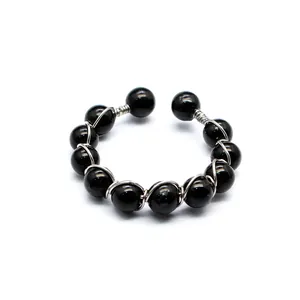 Detailansicht eines handgefertigten verstellbaren Rings mit schwarzen Perlen und Draht.