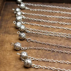 Close-up of vintage silver filigree hollow bead pendants with delicate link chains.