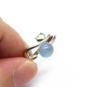 Detail of silver fox-shaped open ring featuring a round light blue aquamarine stone.